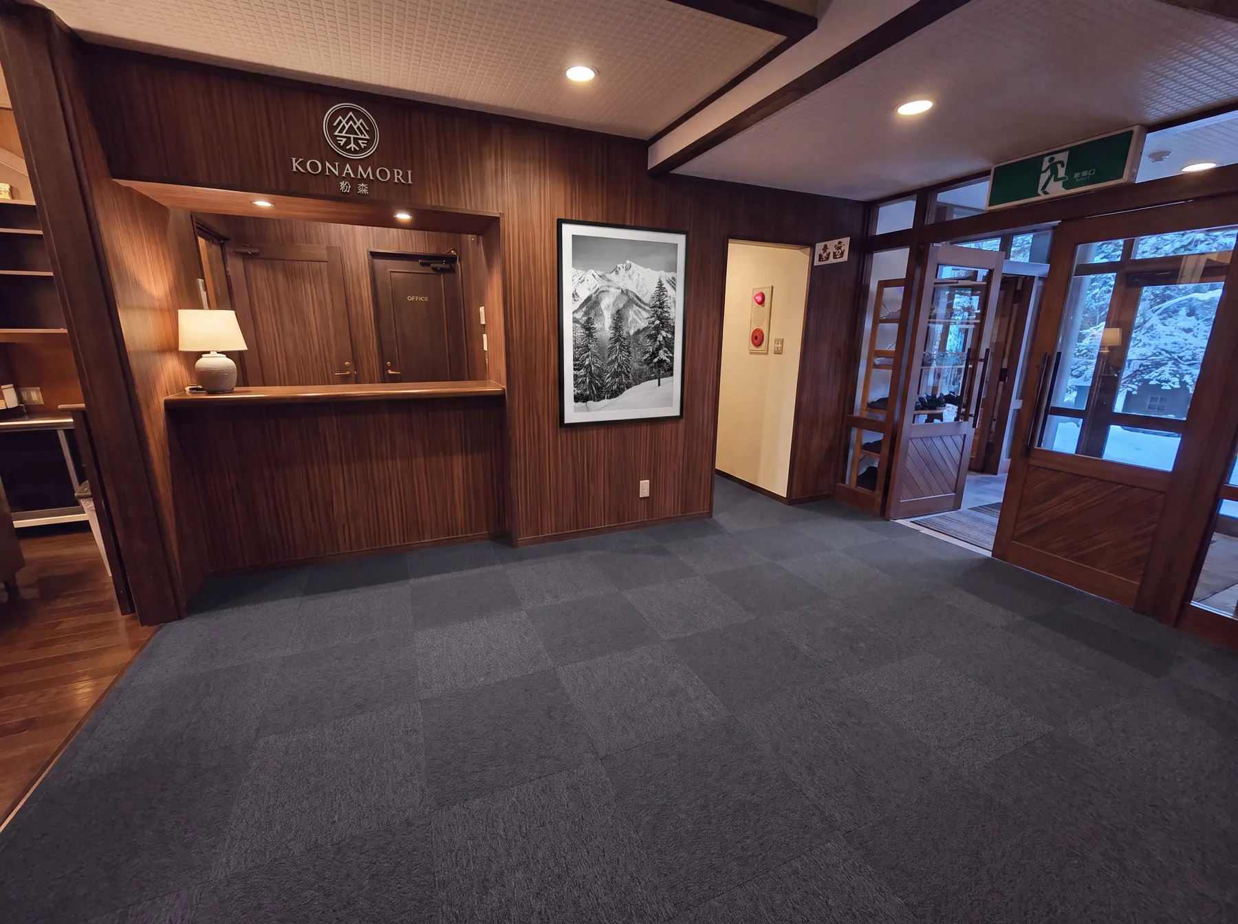 The reception at Konamori: walnut panelling, a single lamp, and a large black-and-white mountain photograph